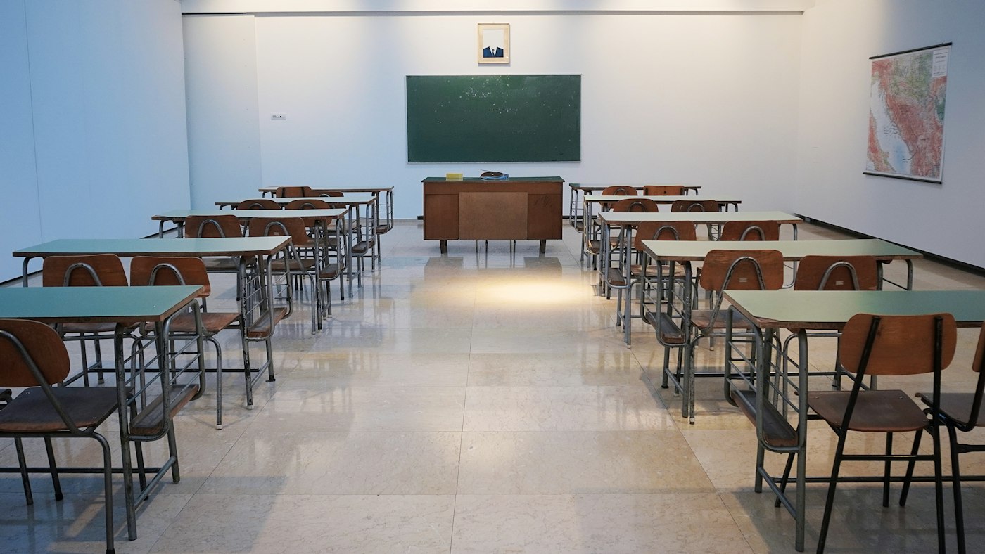 Empty classroom with desks, chairs and a chalkboard